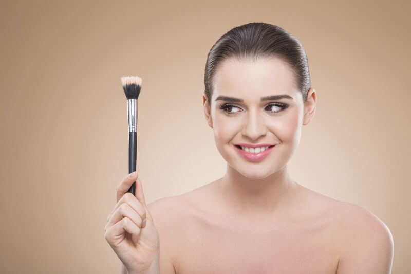 girl posing with make up brush and smiling