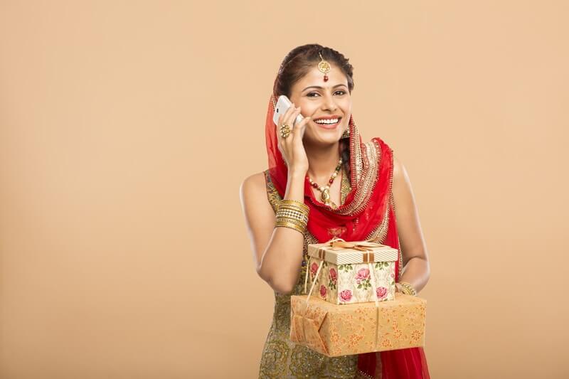 woman talking on phone while holding gifts