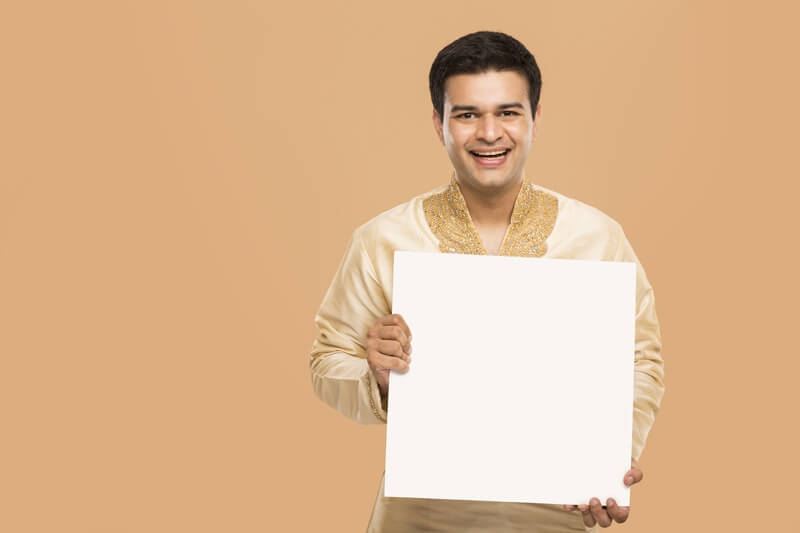 man wearing kurta posing with message board