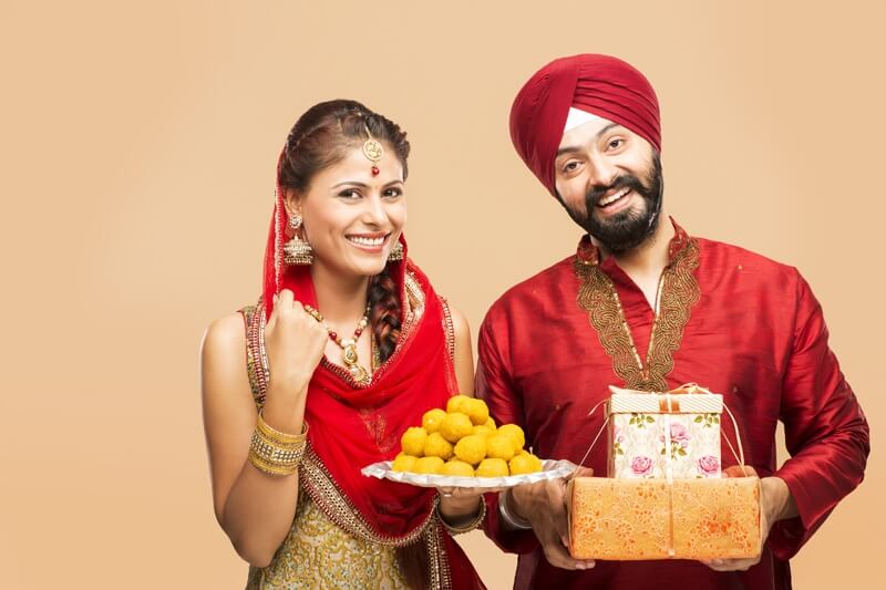 sikh couple posing with gifts and sweets