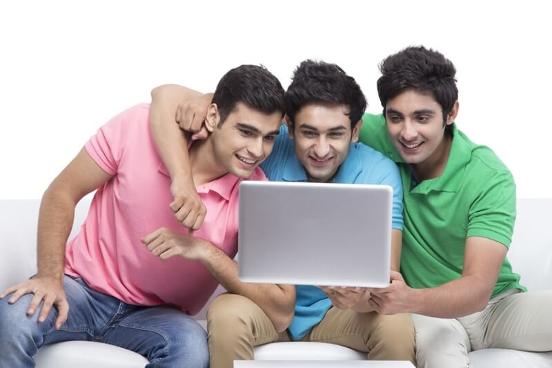 three friends looking at the laptop and smiling