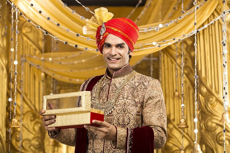 indian groom posing with a gift box
