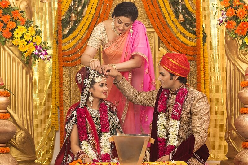groom applying sindoor to wife
