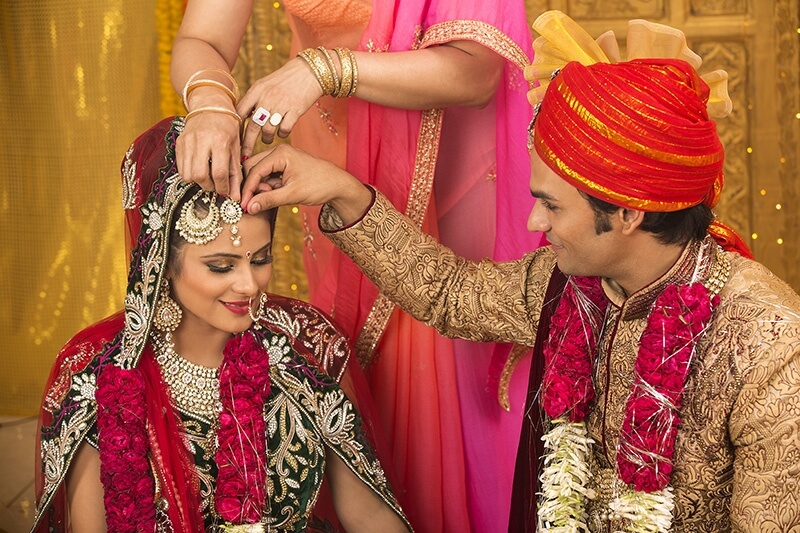 groom applying sindoor to wife