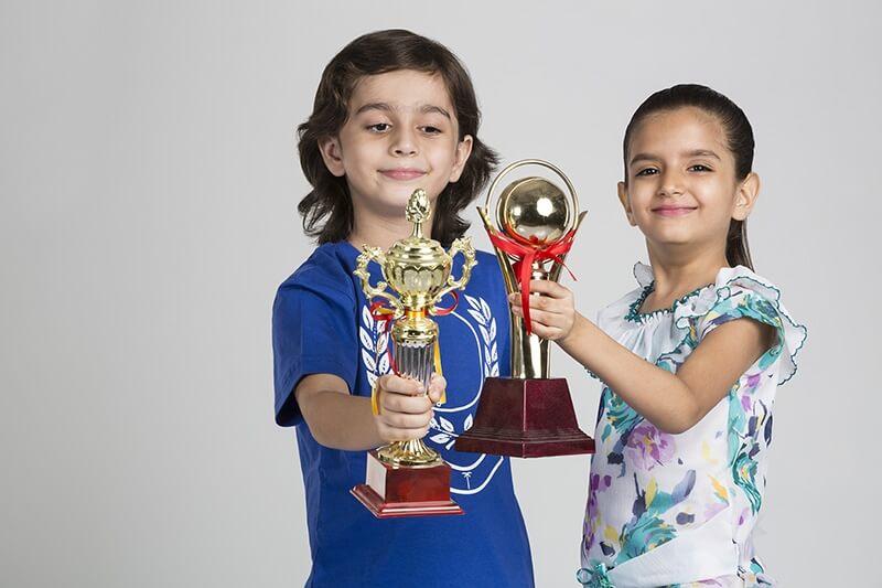 kids smiling and posing with trophies
