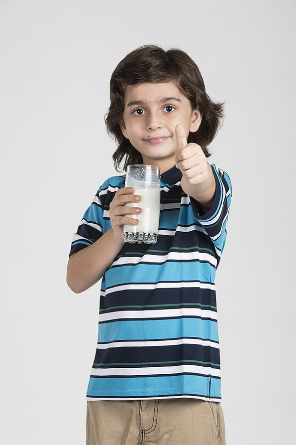 child showing thumbs up with a glass of milk