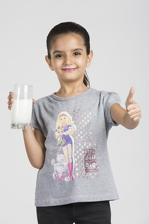 child showing thumbs up with a glass of milk