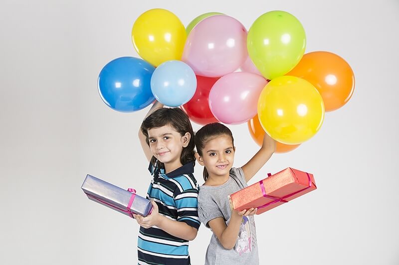 kids posing with balloons and gifts