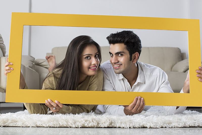 young couple posing with wooden frame at home
