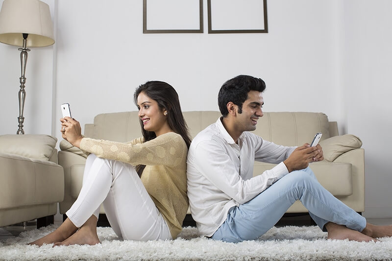 couple at home chatting on mobile phone