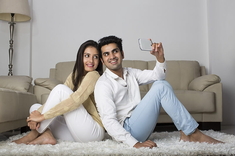 couple clicking picture with mobile phone at home