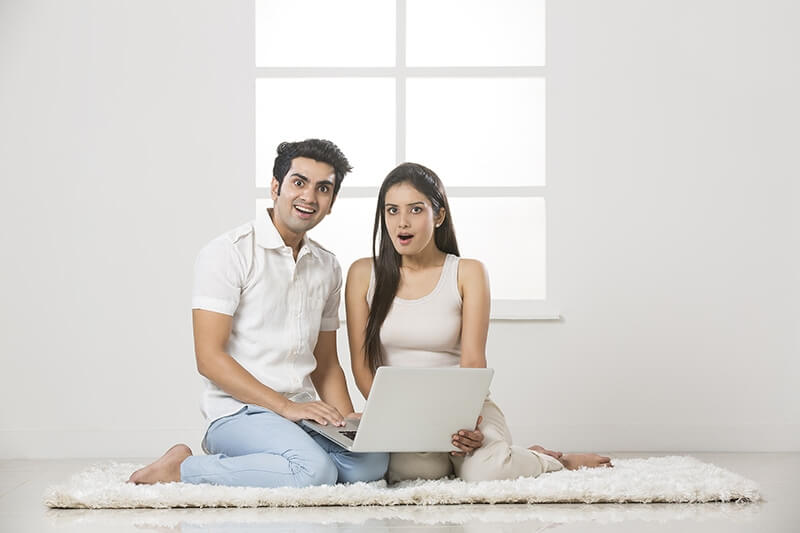 couple with surprised gesture while working on laptop