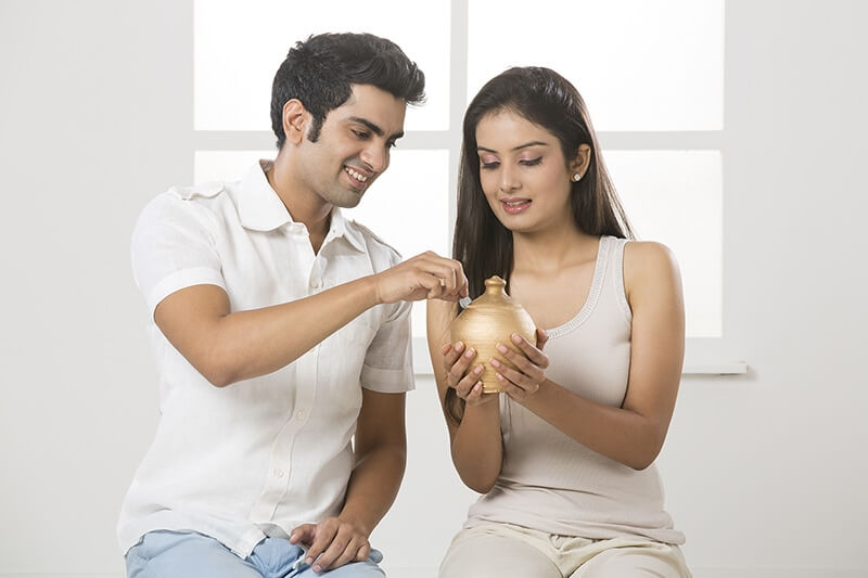 newly wed couple at new home with piggy bank