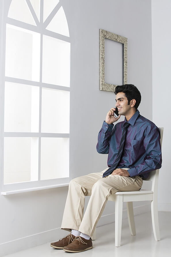 man sitting on chair talking on mobile phone
