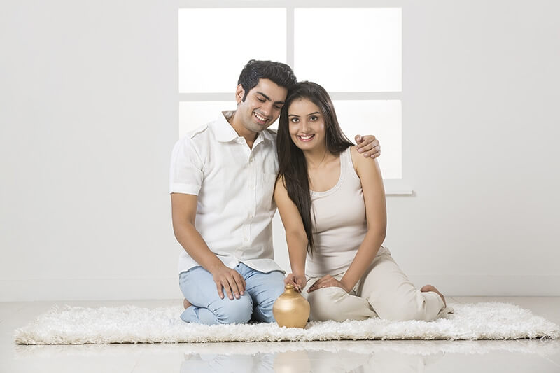 newly wed couple at new home with piggy bank