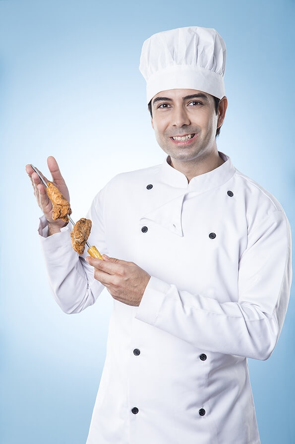 indian chef posing with dish