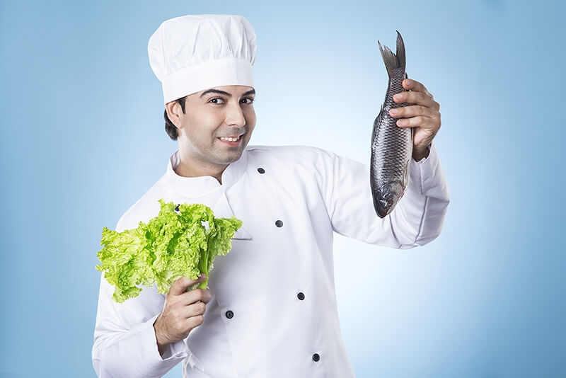 chef posing with fish and lettuce