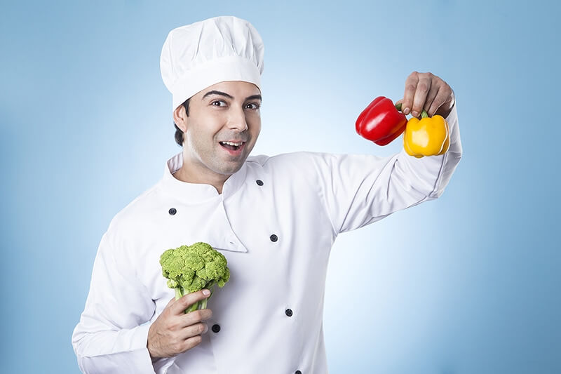 chef posing with capsicums and broccoli