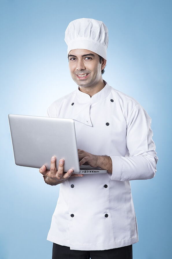 chef smiling and posing with laptop