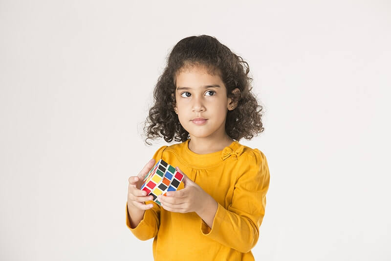 adorable little girl playing with cube puzzle