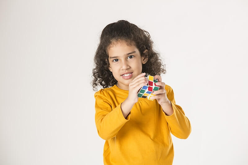 adorable little girl playing with cube puzzle