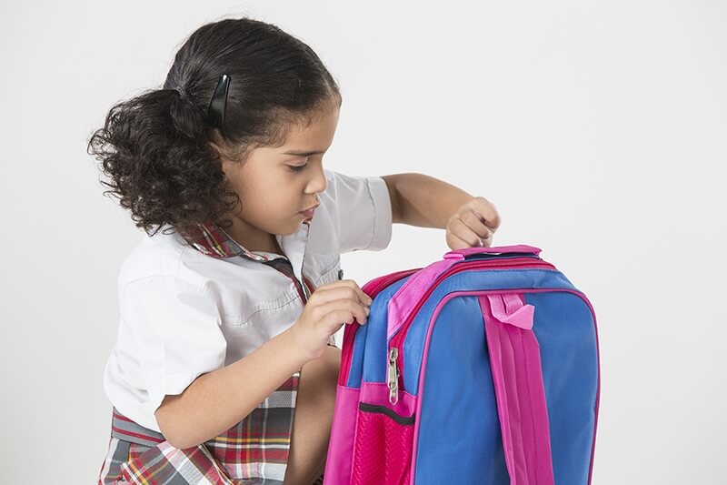 girl zipping her school bag 
