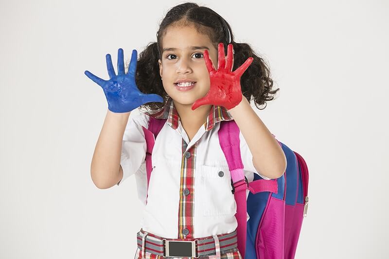 little girl in school uniform with painted hands 