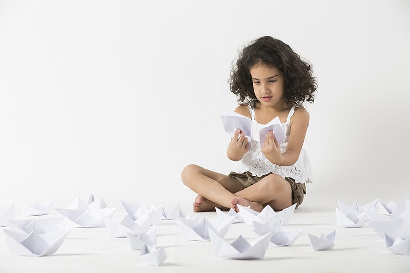 cute little girl playing with paper boat 