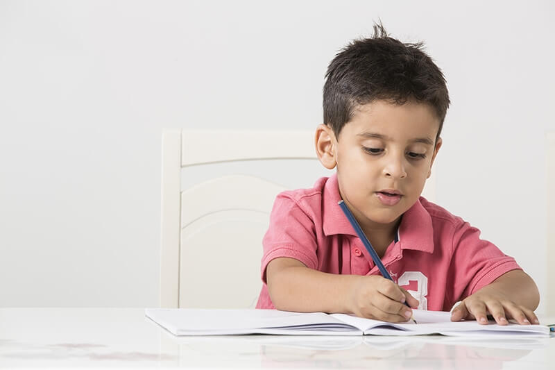 cute little boy studying on table