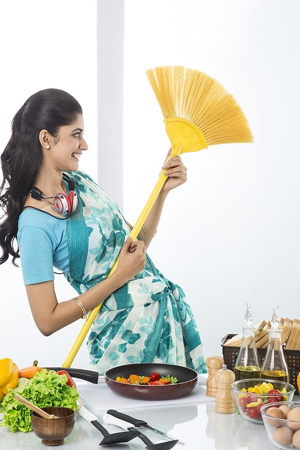 housewife in kitchen dancing with broom
