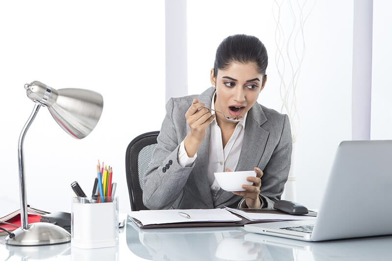 business woman eating cornflakes while working