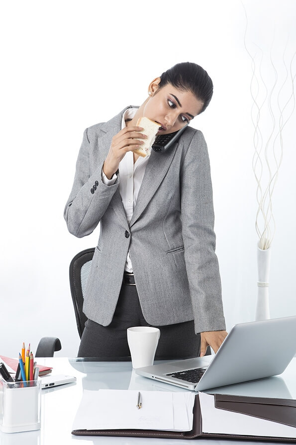 modern woman eating sandwich while working 