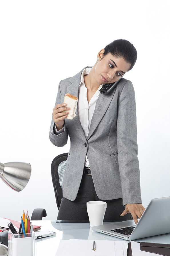 modern woman eating sandwich while working 