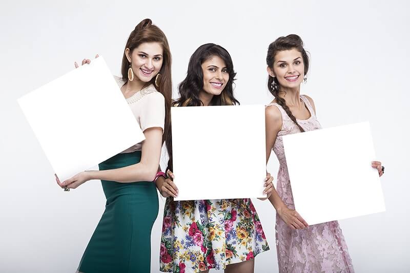 three young women posing with message board