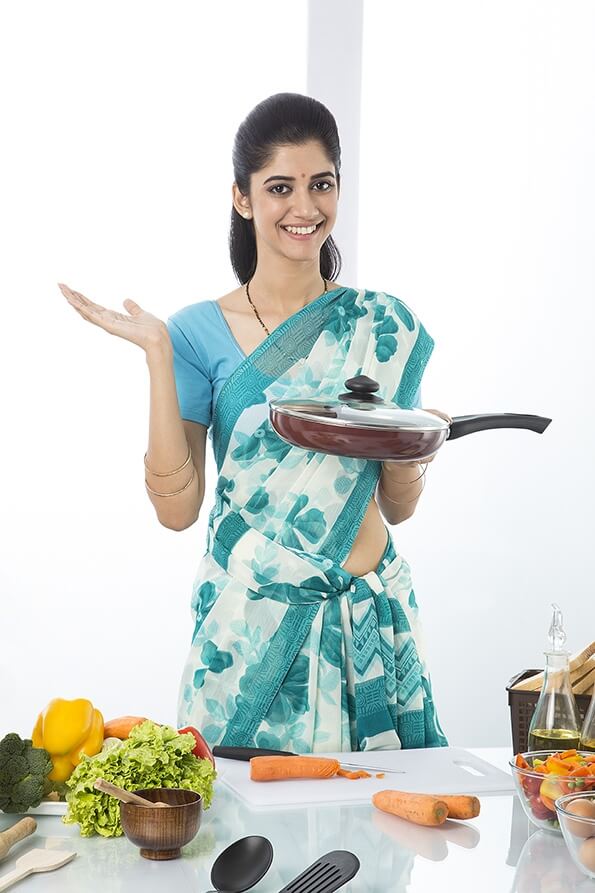 Indian housewife showing pan in kitchen