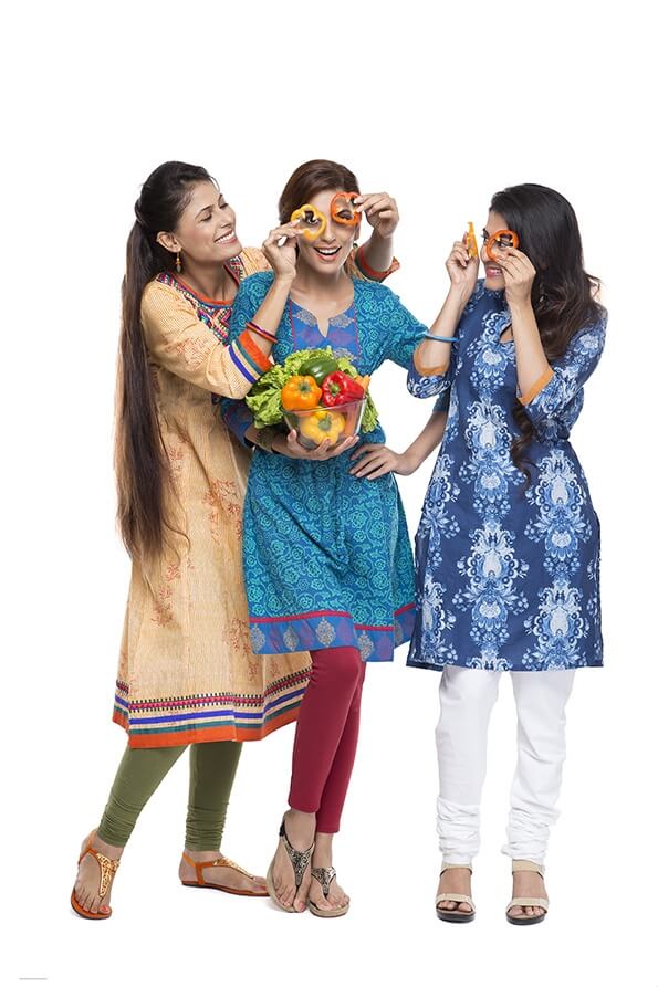 three women standing together holding vegetable in hand