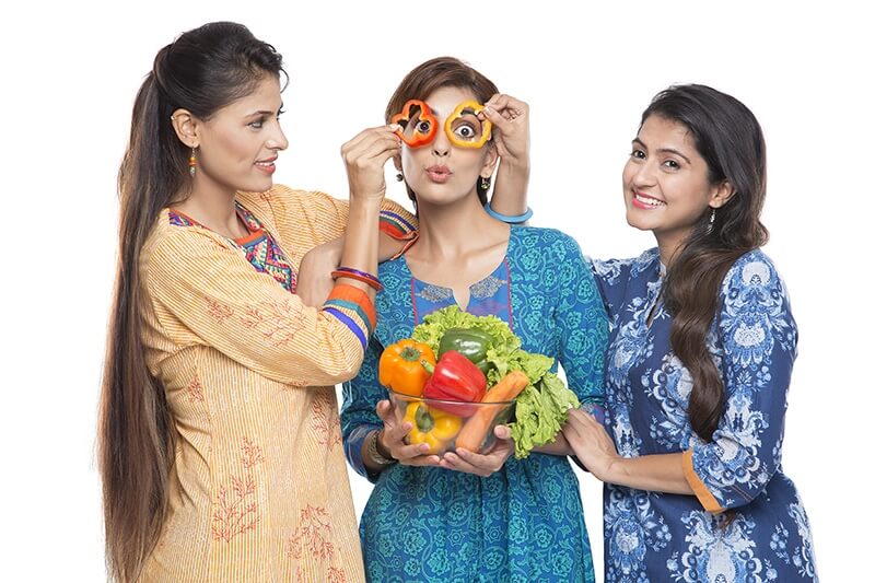 three women standing together holding vegetable in hand