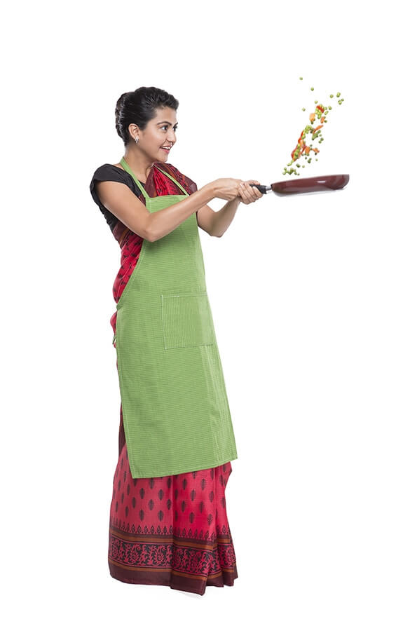 women wearing apron and tossing vegetables in fry pan