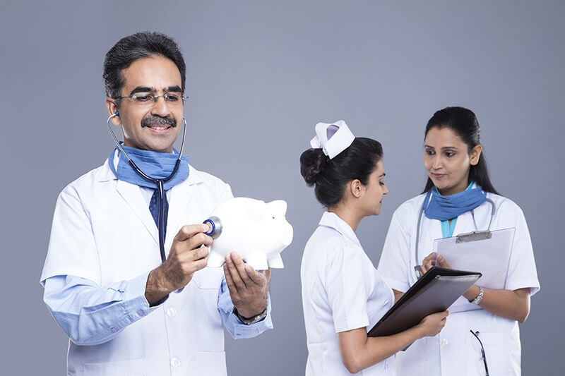 doctor with stethoscope holding piggy bank behind medical staff