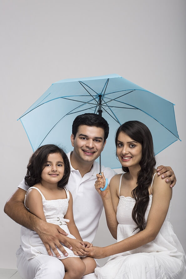 young family sitting together holding umbrella