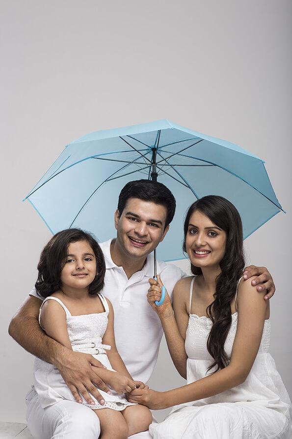 young family sitting together holding umbrella