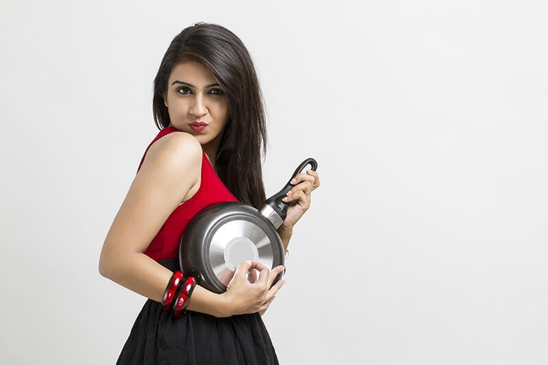 young woman holding fry pan in hands