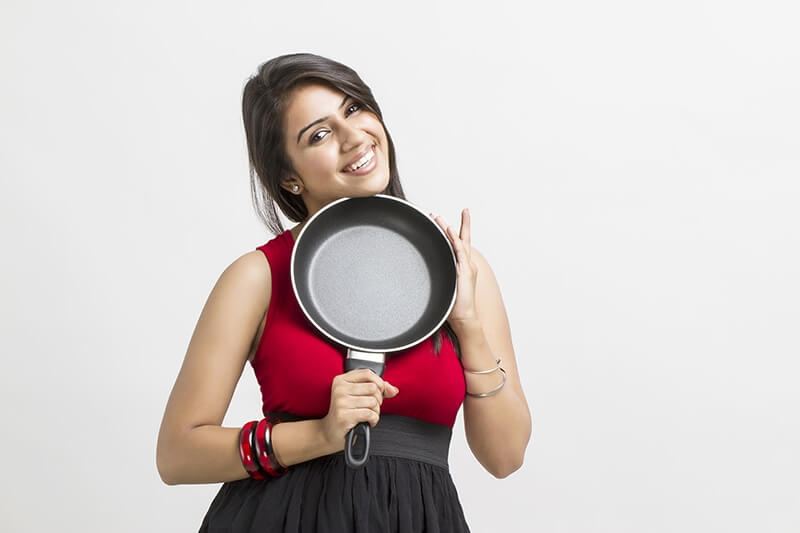 young woman holding fry pan in hands
