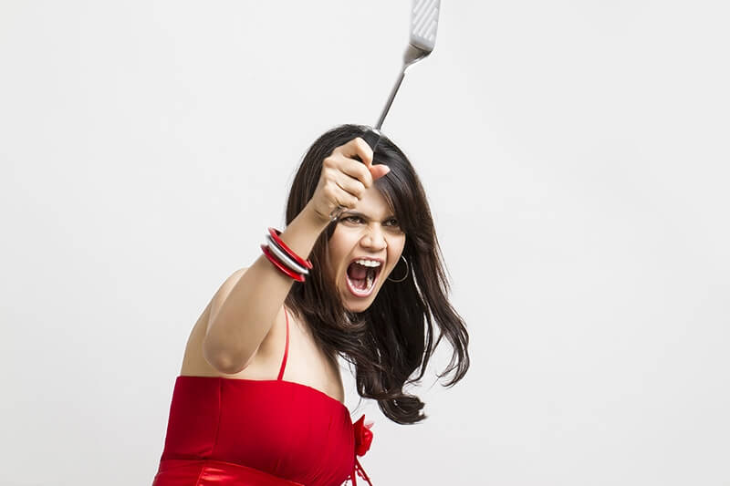 young woman shouting with holding spatula in hands