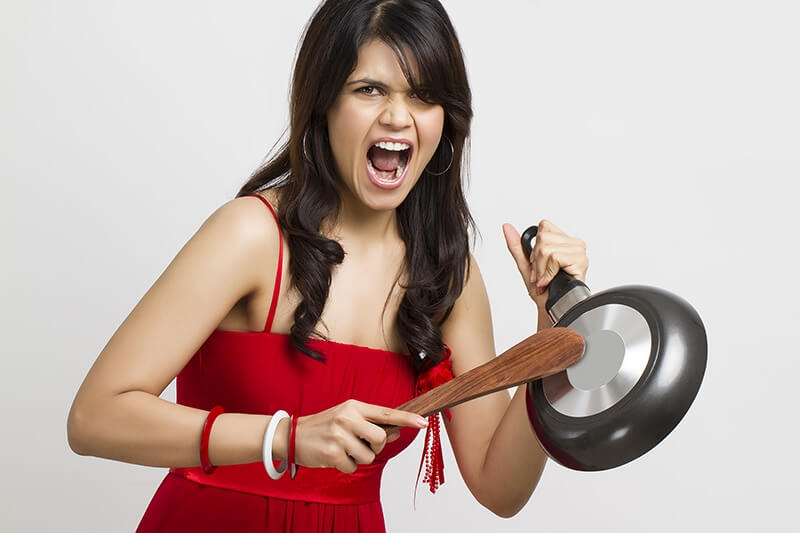 young woman shouting with kitchenware in hands