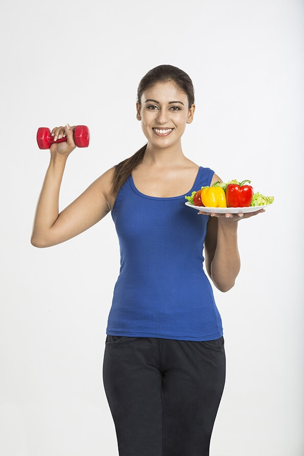 healthy woman with vegetables and dumbbell