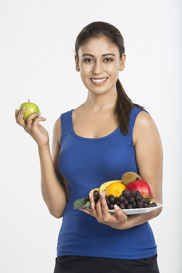 young woman yellow apple with full plate of fruits