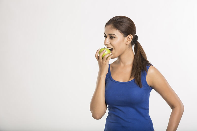 Young women eating yellow apple