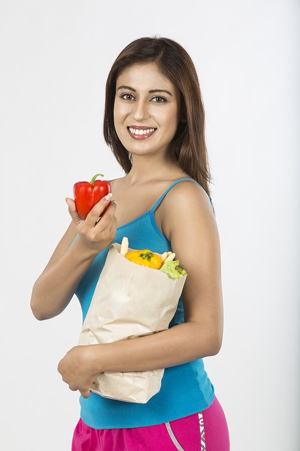 Young girl left hand holding bag full of vegetables with red capsicum 