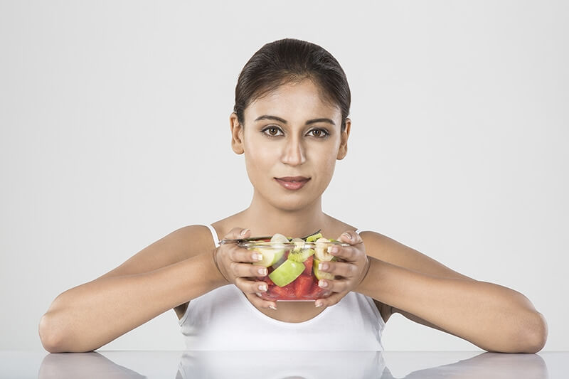 young woman holds fruit bowl
